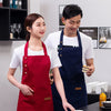 A woman in a red apron stands next to a man in a navy blue apron, both in a bright kitchen setting.