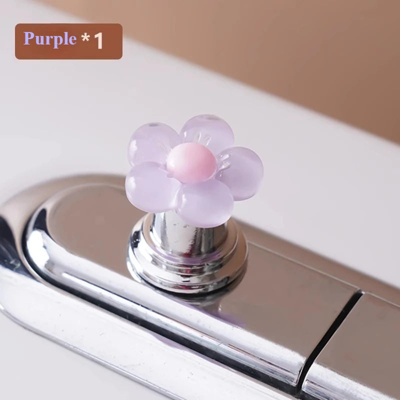 A purple flower-shaped toilet flush button is shown on a chrome fixture.