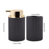A black foaming soap dispenser with a gold cap and a toothbrush holder, shown in a side view.