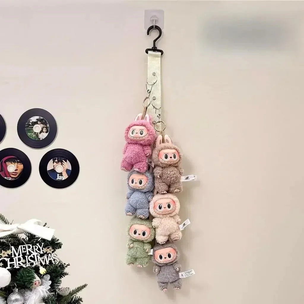 A display rack featuring several plush Labubu figures hanging from a hook on a wall.