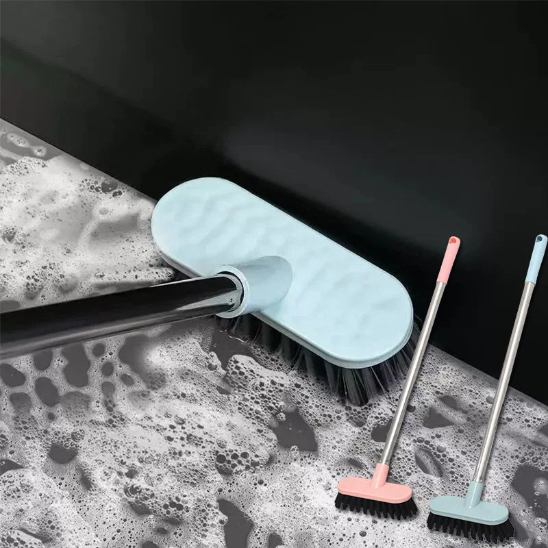 A long-handle floor scrub brush with a light blue head is shown cleaning a wet, soapy surface.