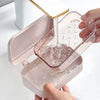 A hand is pouring water into a transparent drainage soap dish, which is part of a pink dispenser.