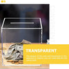 A transparent acrylic cube piggy bank filled with stacked US dollar bills on a wooden surface.