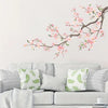 Decorative peach tree branches with pink blossoms displayed on a white wall.