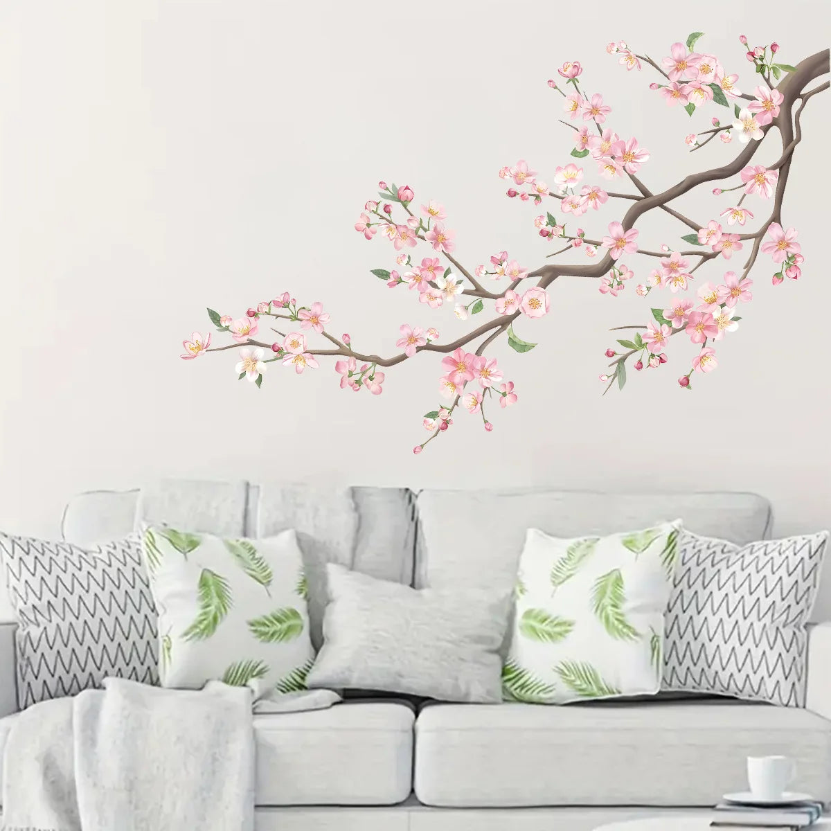Decorative peach tree branches with pink blossoms displayed on a white wall.