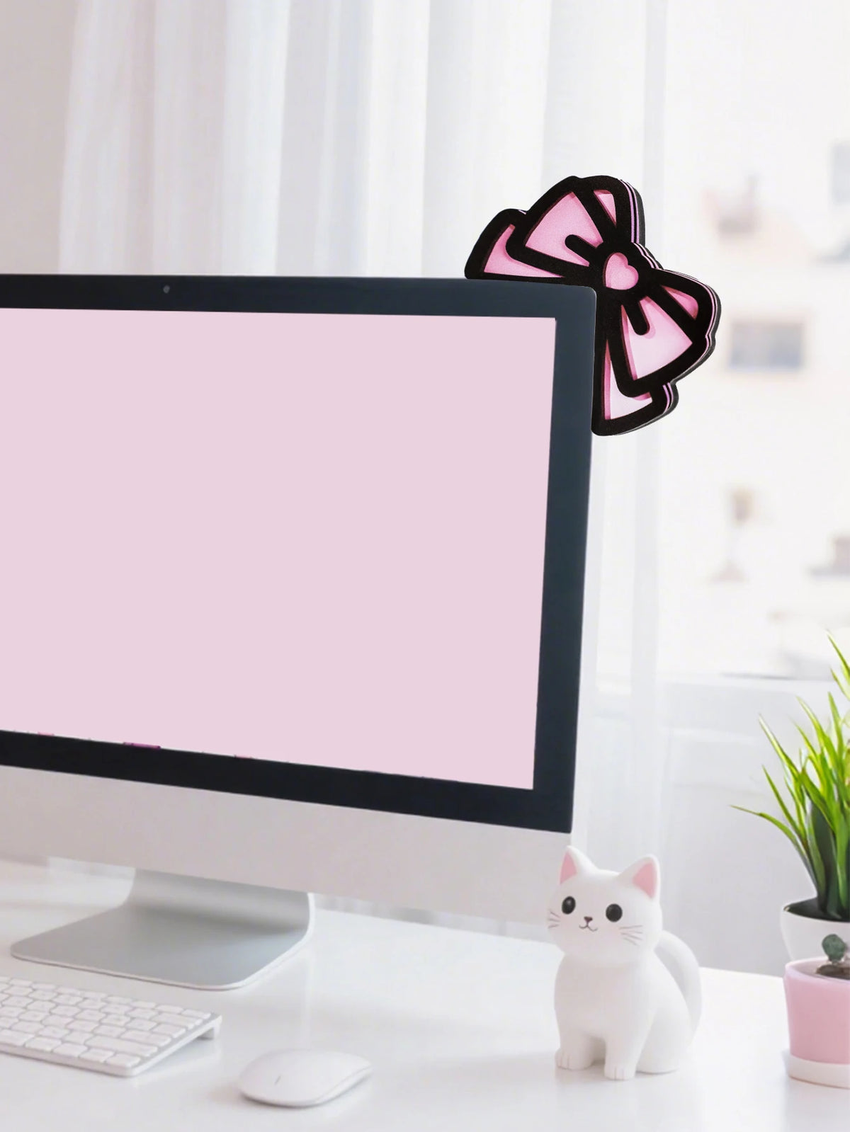 Figurine de chat blanc à côté d'un moniteur affichant un fond et un nœud rose.