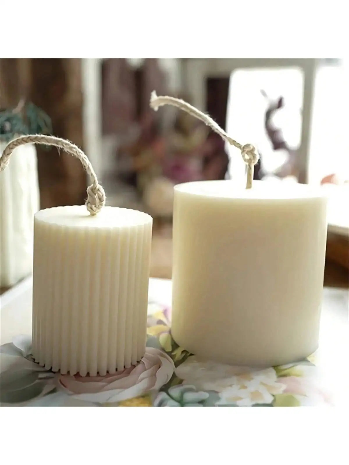 Dos velas de pilar blancas con mechas de yute naturales exhibidas en una superficie.