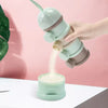 A hand pours white powder from a layered silicone food storage box into another container against a pink background.