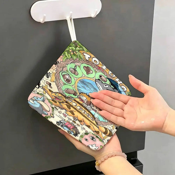 A hand is wiping a Totoro cartoon hanging towel on a dark surface.