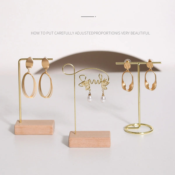 A wooden jewelry display rack holds gold-toned earrings and a delicate necklace.