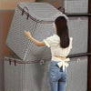 A woman in a white top and jeans is interacting with a stack of black and white checkered storage boxes.
