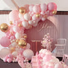 A pink and gold balloon garland decoration featuring round foil balloons and white balloons for an event backdrop.