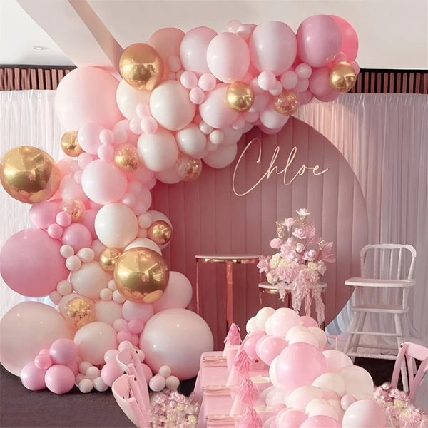 A pink and gold balloon garland decoration featuring round foil balloons and white balloons for an event backdrop.