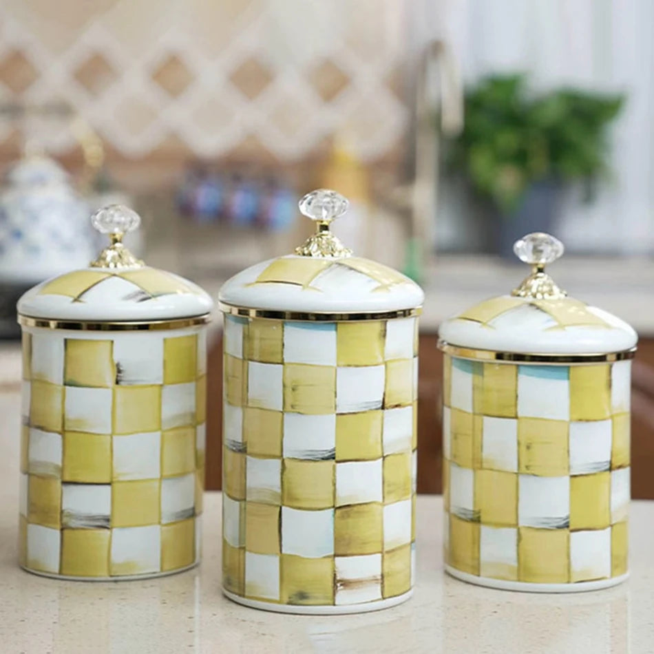 Three retro enamel storage jars with gold lids and a white and gold checkered pattern.