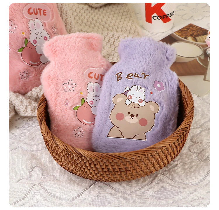 Two pink and purple plush cartoon hot water bottles are displayed in a woven basket on a white fabric surface.