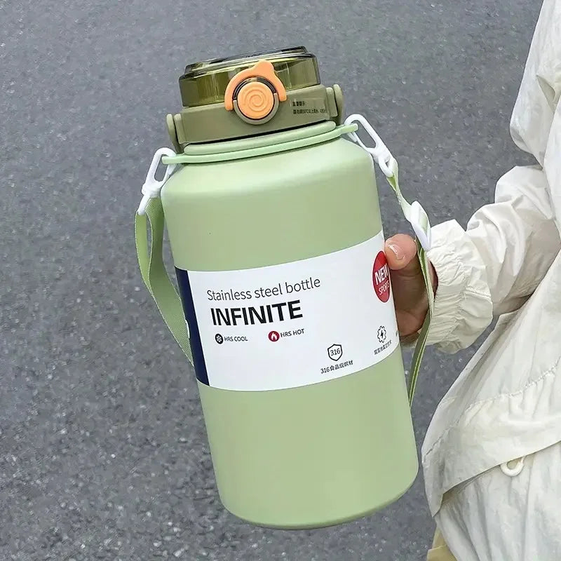 A light green stainless steel insulated tumbler with a lid and handle is held by a person.