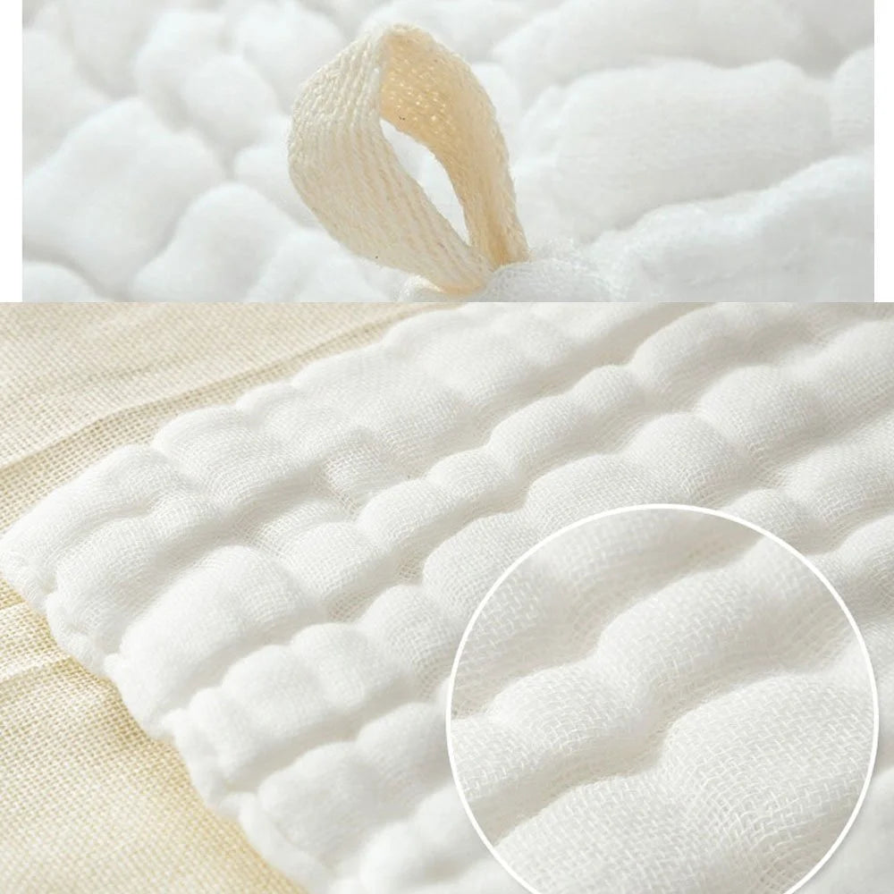 Nahaufnahme eines weißen Baumwoll-Muslin-Waschlappensets mit strukturiertem Stoff und einem gerollten Tuchstück.