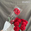 Un bouquet de cœurs de coton rouges faits à la main, présentés dans une gaine en plastique transparent.