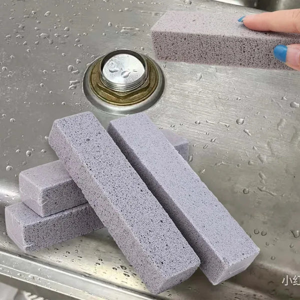 Several grey pumice stone sticks are displayed on a metal surface next to a round metal object.