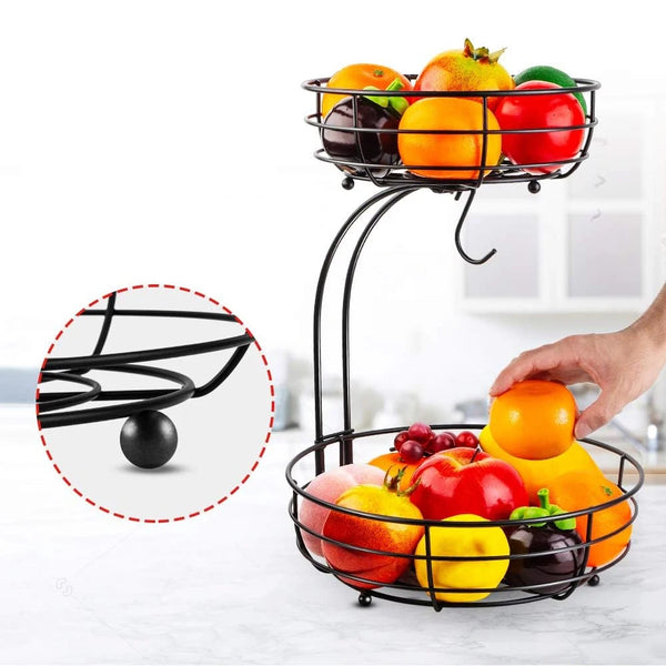A black metal two-tier fruit basket organizer filled with various colorful fruits like apples, oranges, and plums.