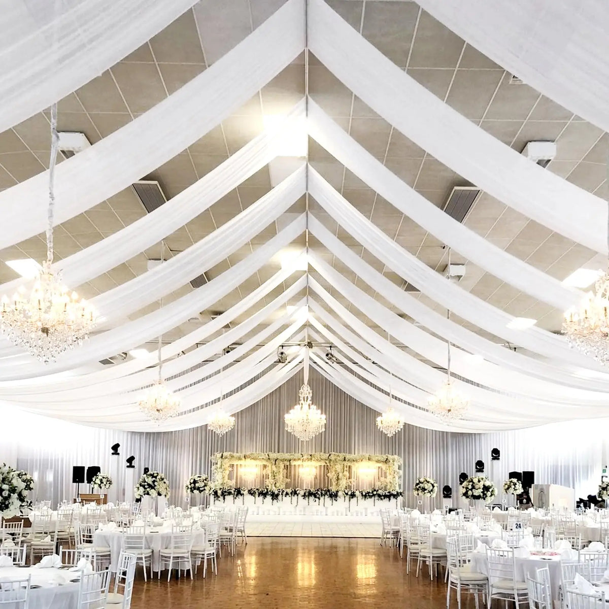 Elegant white sheer chiffon draping fabric creating a flowing ceiling canopy for an event venue.