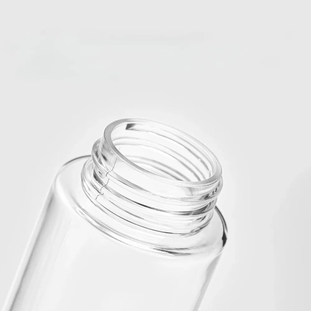 A clear glass bottle with a silver cap, showing the top portion of a refillable styling mist spray bottle.