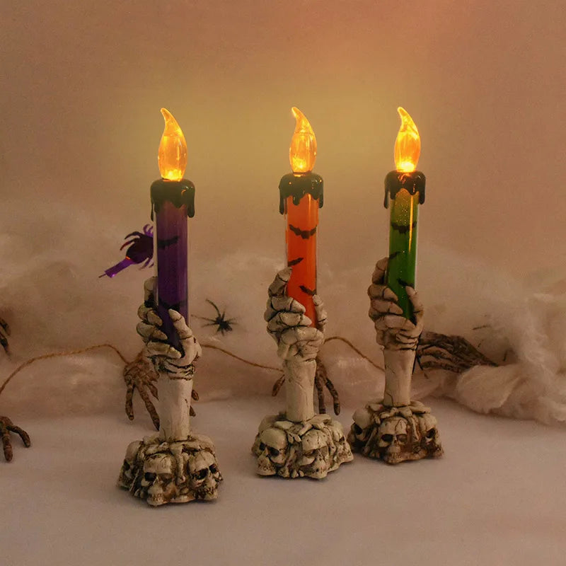 Three skeleton hand shaped LED candles with flickering flames set against a soft, warm background.