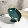 A dark green oval plastic soap dish with a gold rim and drainage holes resting on a white surface.
