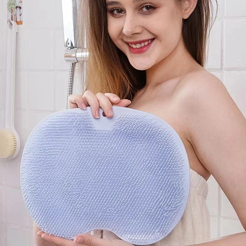 Una mujer sostiene una estera de masaje de pies de silicona azul claro en un espejo del baño.