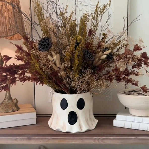 Handmade ceramic ghost vase filled with dried floral and botanical arrangements for Halloween decor