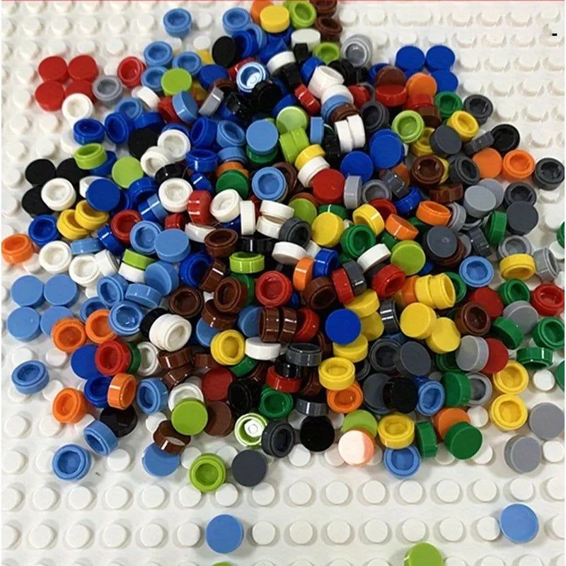 A pile of round building blocks in various colors including blue, green, red, yellow, and black on a white surface.