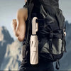 A beige folding umbrella is shown attached to a black backpack.