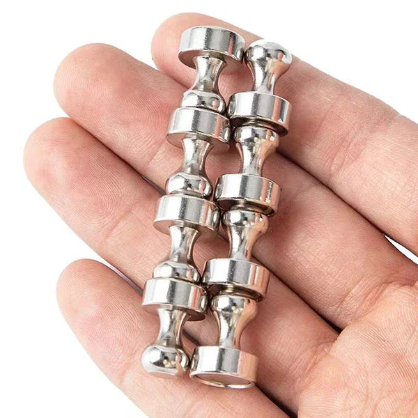 A hand holds a set of heavy-duty magnetic push pins with silver metal heads.