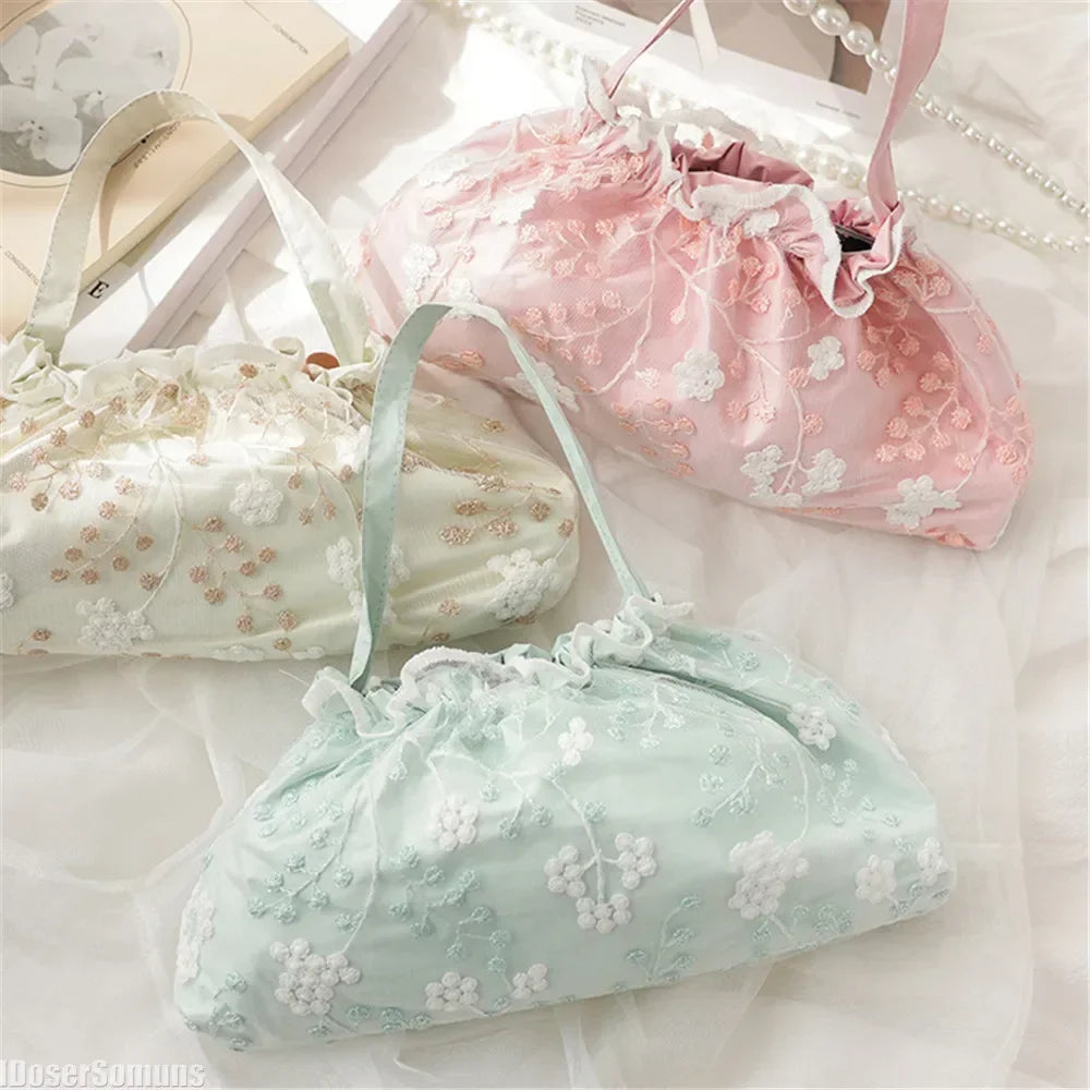 Three light pink and white embroidered fabric bags are displayed on a white surface.