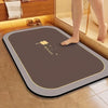 A brown diatomite bath mat is placed on a tiled bathroom floor next to a wooden cabinet.