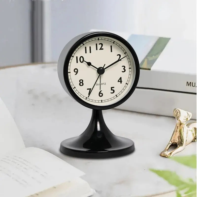 A black round metal alarm clock with a white face and Roman numerals is displayed on a white surface.