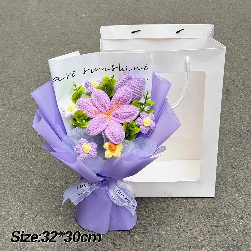 A purple handmade crochet flower bouquet with yellow accents is displayed in a white paper bag.