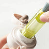 A hand is holding a light green cleaning brush set with a white handle and bristles against a white base.