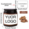 A dark glass jar of ebony agarwood with a custom label and a wooden agarwood piece shown next to it.