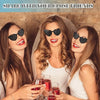 Trois jeunes femmes souriantes tenant des lunettes photochromiques en forme de cœur dans une ambiance festive