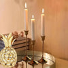 Elegant metal candle holders set of three with lit candles and a decorative pineapple centerpiece