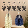 A set of black plastic wig hangers displayed above two wigs, one blonde and one dark blue.