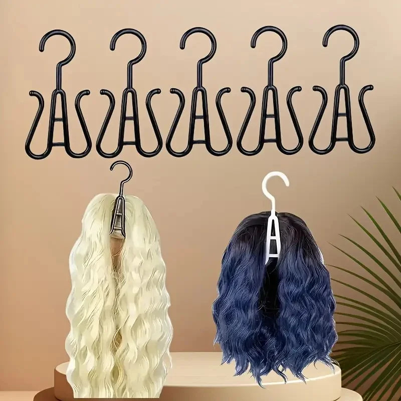 A set of black plastic wig hangers displayed above two wigs, one blonde and one dark blue.