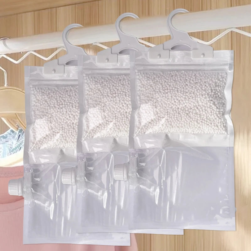 Clear reusable moisture absorber bags with hooks hanging on a wooden rack