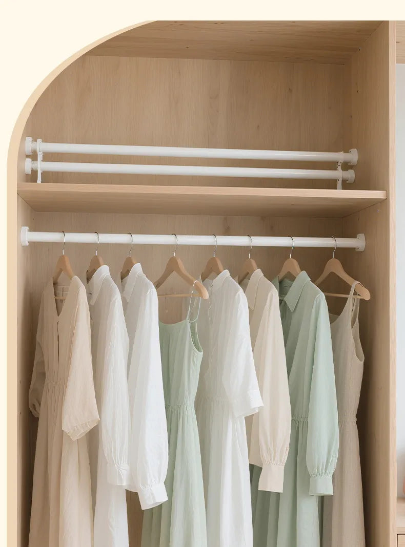 A display of white and light green clothing hanging on a stainless steel shower curtain rod inside a wooden cabinet.