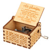A vintage engraved wooden music box with a lid open showing an inscription on the inside.