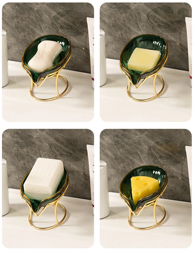 A set of decorative leaf soap dishes featuring white and yellow bars on gold-toned metal stands.