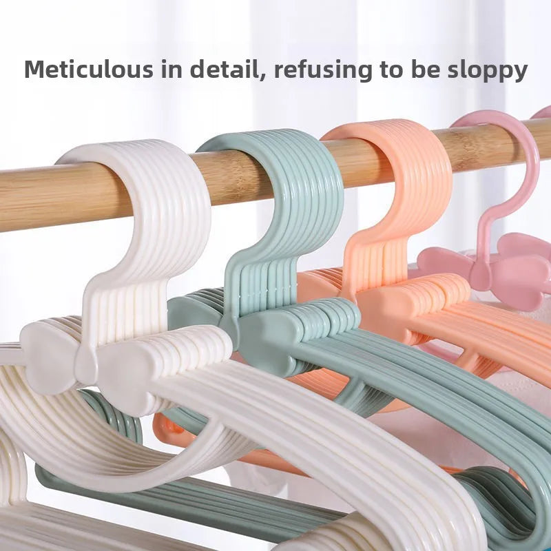 A collection of plastic hangers with bow designs in various pastel colors hanging from a wooden rod.