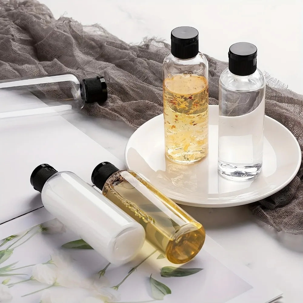 A set of three glass refillable travel bottles with black caps and yellow liquid sitting on a white plate and gray fabric.