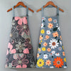 A gray apron with a floral print featuring pink, orange, and yellow flowers hanging on a wooden hanger.